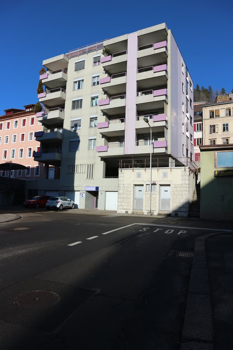 Apartment building, balconies, underground parking, two parked cars