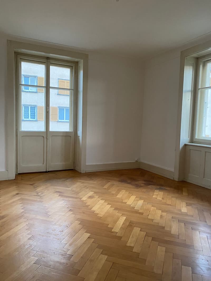 empty room, parquet flooring, white walls, white doors, two large windows, city view