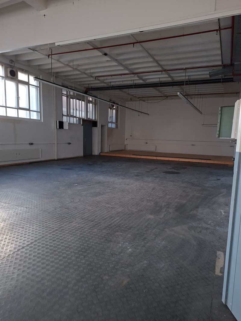 open floor, metal flooring, windows, pipes on ceiling