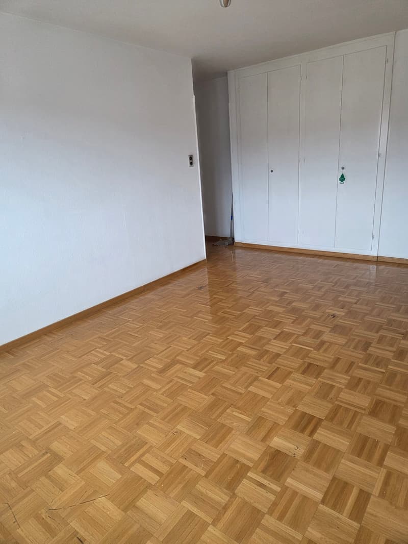 Empty room with wooden floor, white walls, white closet, and power outlet on the left wall