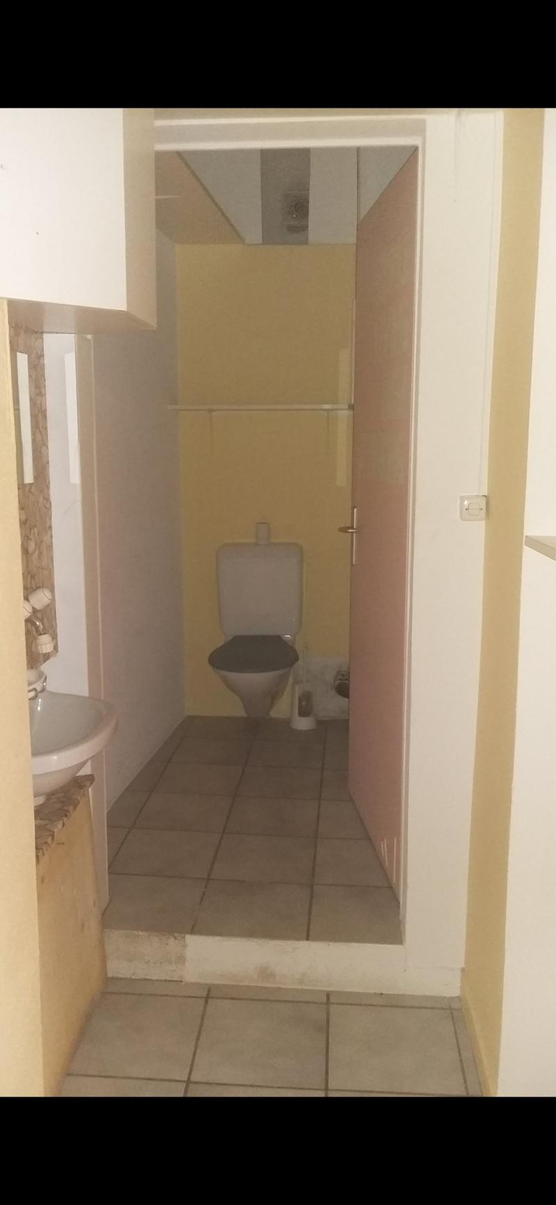 A bathroom with toilet, sink, tiles floor, mirror
