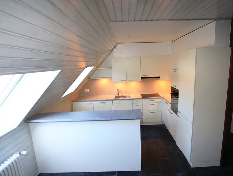 Modern kitchen with white cabinets, tile countertops, sink, stove, oven, two skylight windows