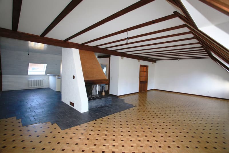 Fireplace in the corner, wooden parquet flooring, wooden beams on ceiling