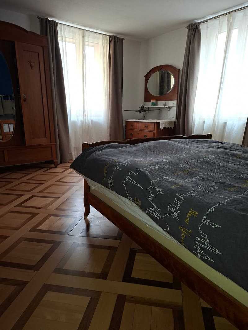 wooden bed, patterned wooden floor, wooden wardrobe, vanity with mirror, small shelf