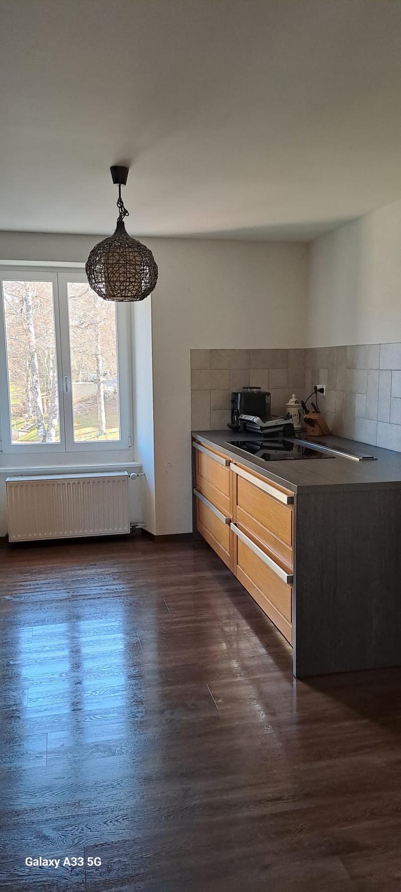 modern kitchen, wooden floor, white walls, large window, kitchen island, hanging lamp, radiator