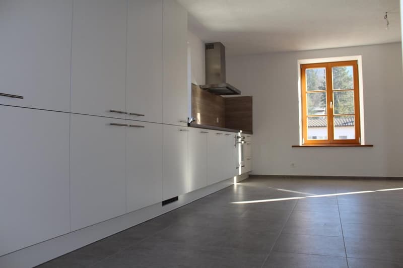 modern kitchen with white cabinets, gray tiled floor, stainless steel range hood, window with wooden frame