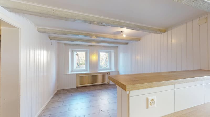 empty room, wooden beams on the ceiling, white wooden walls, radiator, wooden countertop, tile flooring, wooden window frames