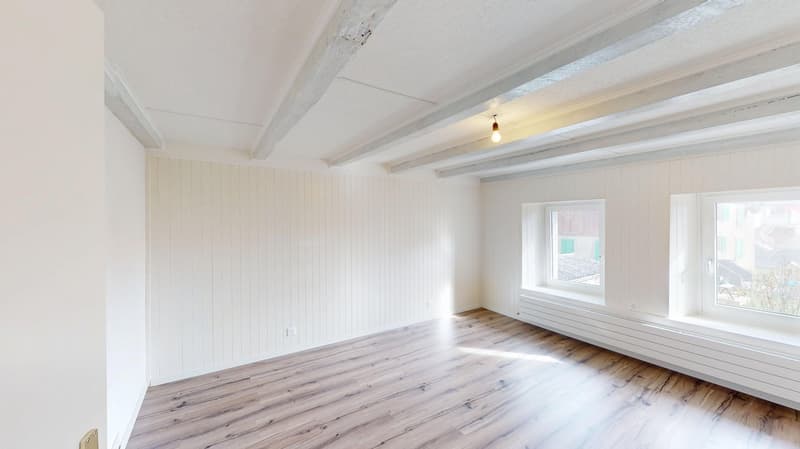 white walls, wooden floor, white ceiling beams, two windows