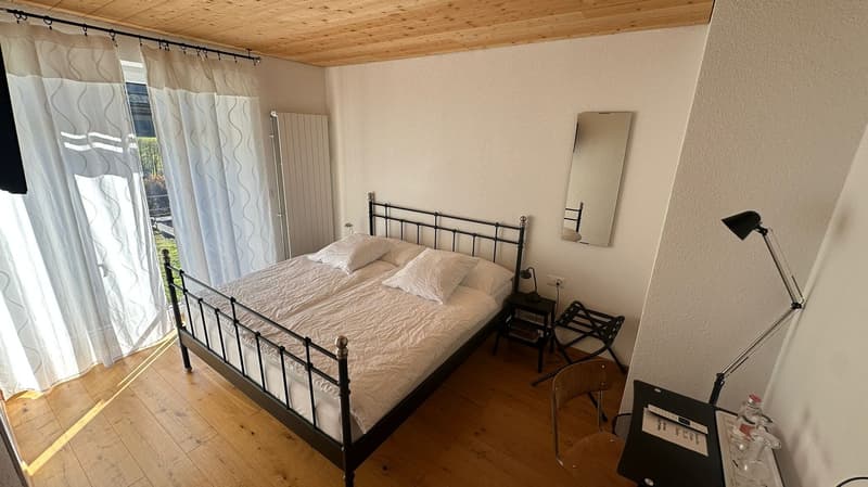 double bed, white bedding, pillows, nightstand, desk, chair, lamp, radiator, mirror, curtains