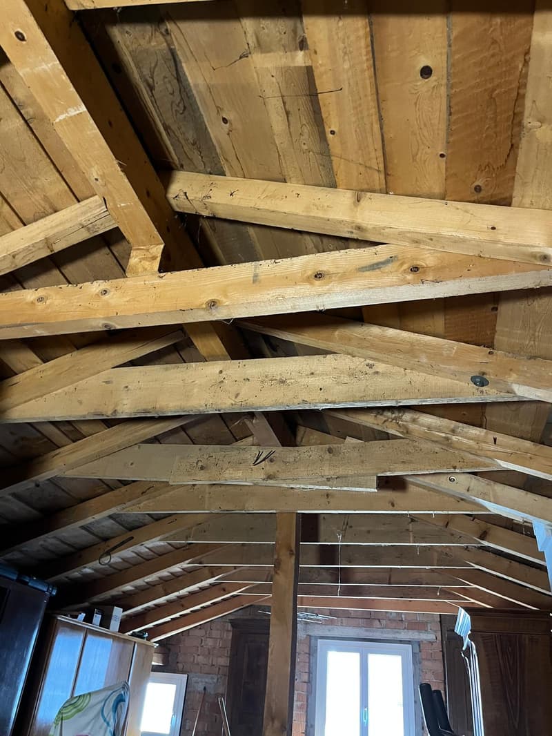 Wooden attic ceiling beams, white windows, brick walls