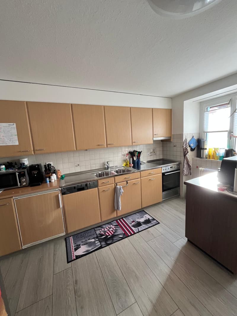 Wooden cabinets, tiled wall, stainless steel sink, dishwasher, washing machine, oven, window