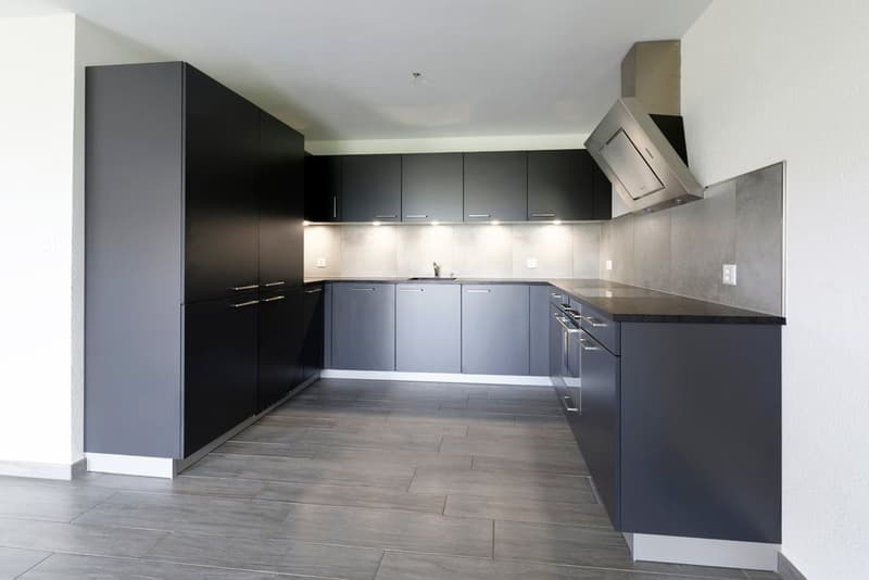 modern kitchen with gray cabinets, black countertops, stainless steel range hood, and tiled flooring