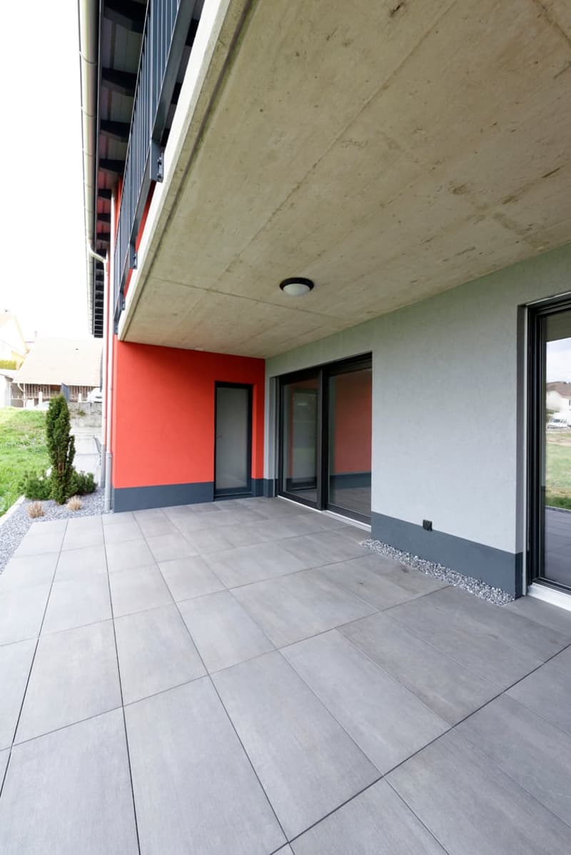 modern building with red and gray walls, large glass doors, tiled floor, and a ceiling light