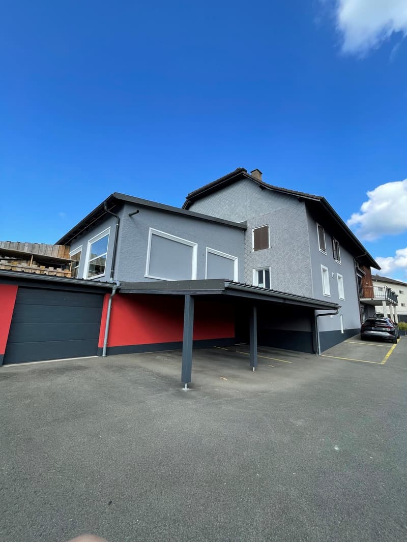 3-story house, gray exterior, red garage door, car parking area