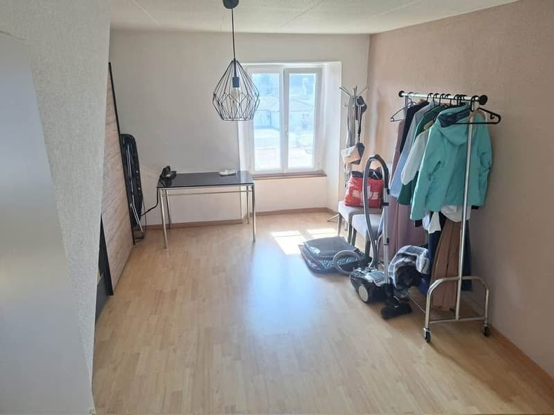 empty room, wooden floor, white walls, window, table, clothes rack, vacuum cleaner