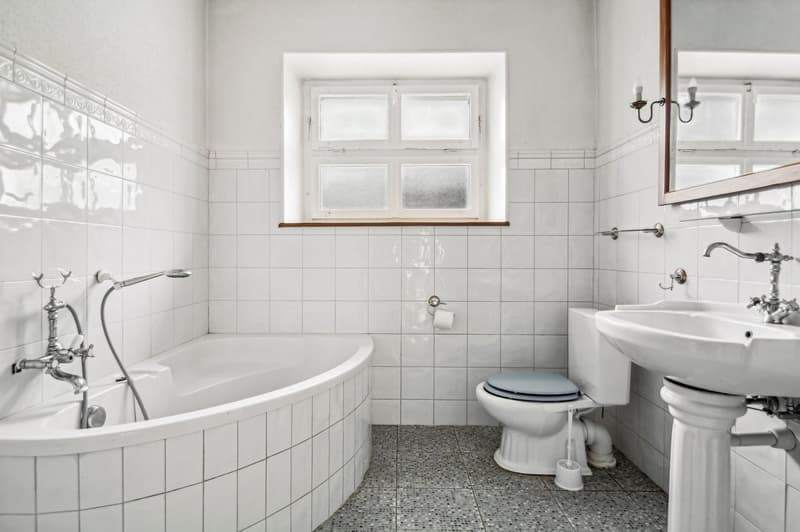 Bathroom with white tiles, bathtub, toilet, sink, mirror, and window