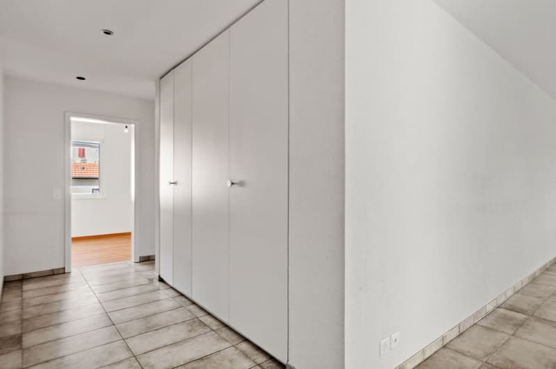 Empty room, white walls, wooden flooring, closets, an open door leading to another room
