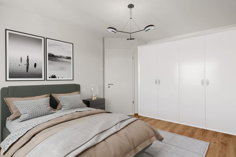 Bed with gray and beige bedding, bedside table with lamp, large white wardrobes, two black and white photos on the wall, wooden floor, gray rug.