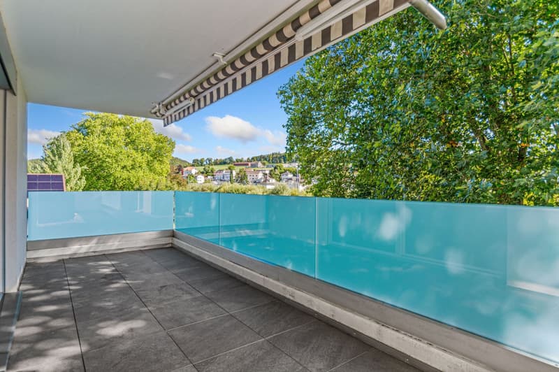 Modern balcony with blue glass railing, view of surrounding town
