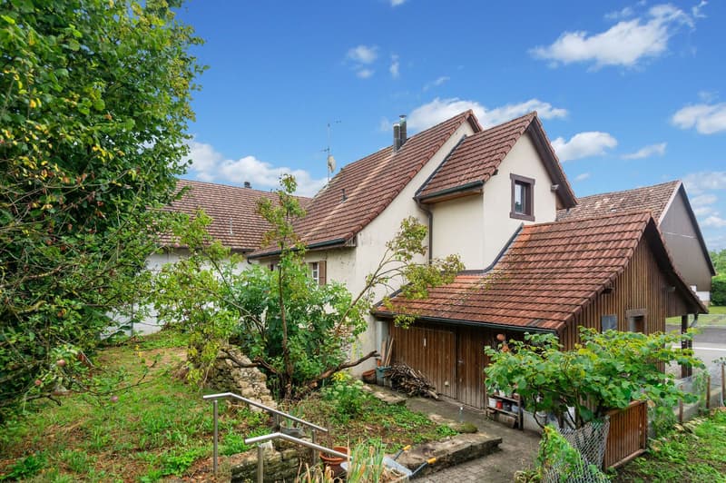 House with red tile roof, white walls, wooden garage