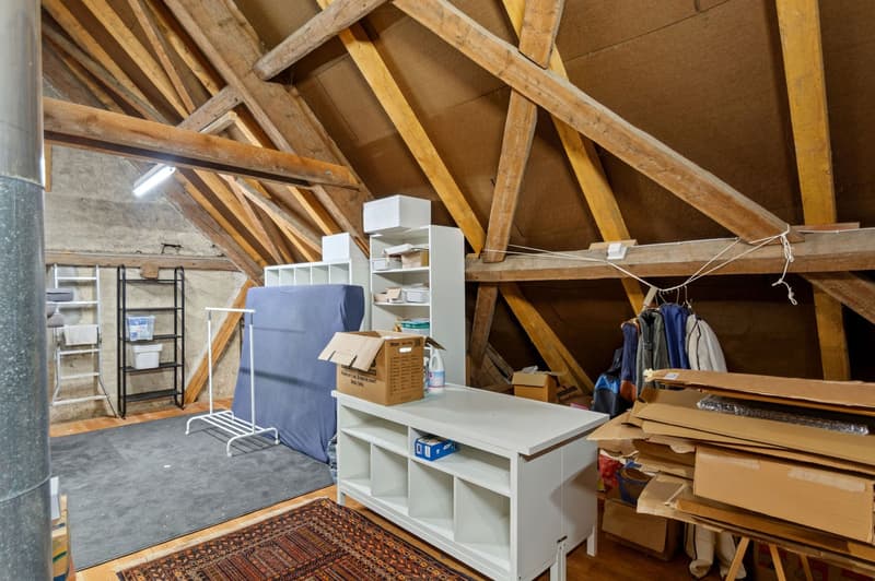 Wooden beams ceiling, rug, white furniture, boxes, blue mattress, wooden racks