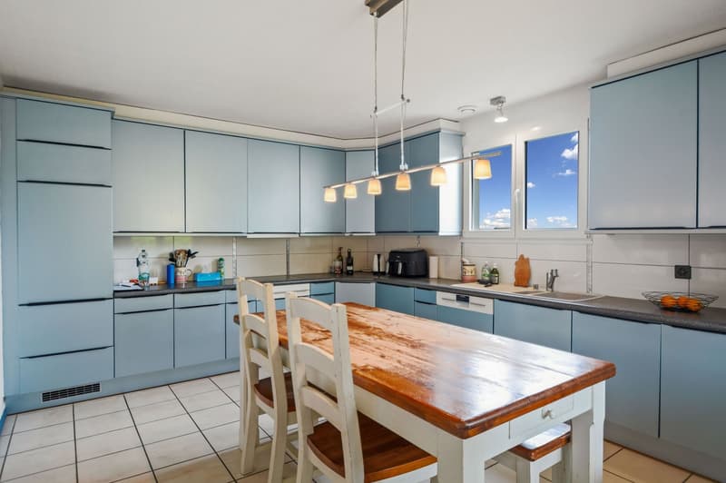 Blue cabinetry, dining table, wooden table, chairs, countertop, sink, windows, lamps