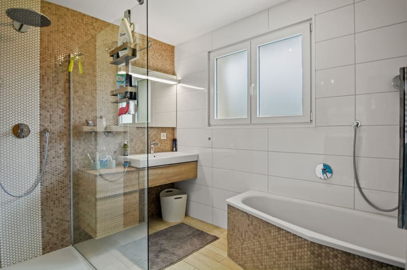 modern bathroom with bathtub, sink, and shower. Tiled walls and floor.