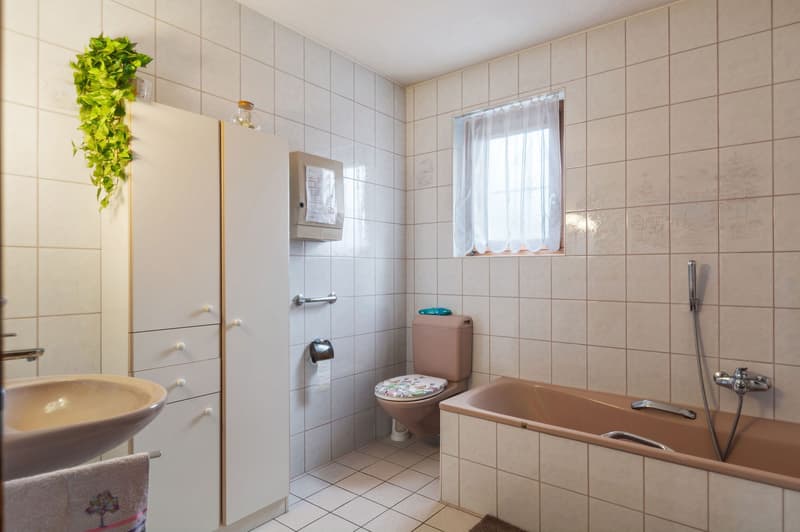 Bathroom with white tiles, toilet, bathtub, shower, sink, cabinet with drawers