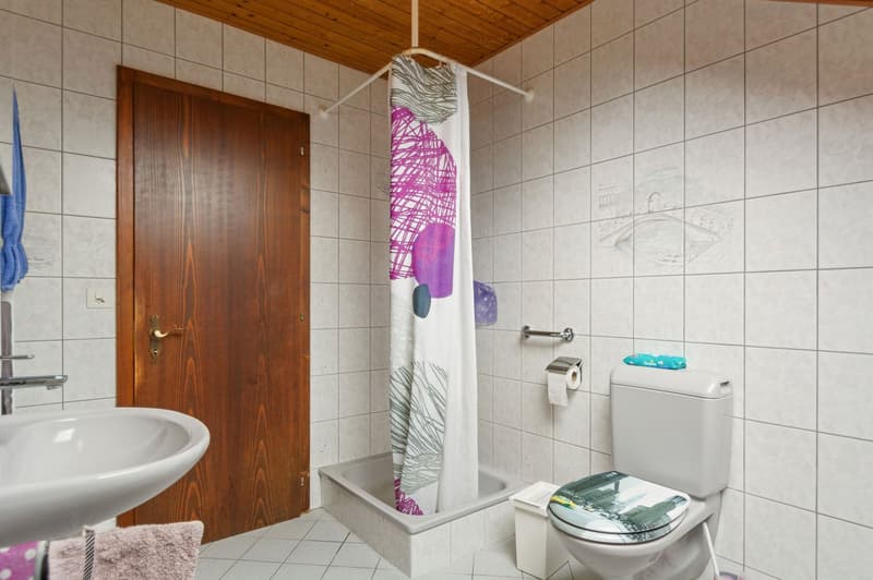 white tiles, sink, toilet, shower, wooden door, power outlet