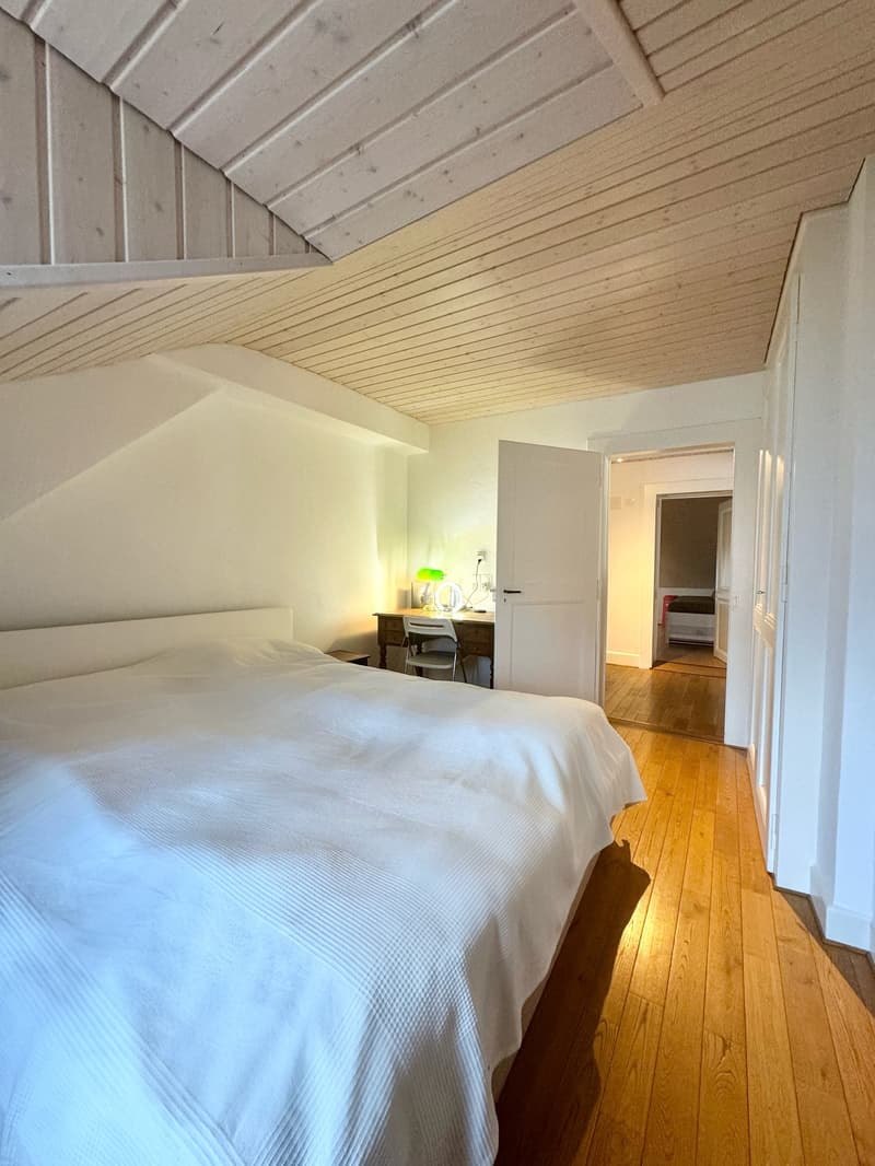ample space, wooden floor, white walls, large bed, desk, chair, white bedding