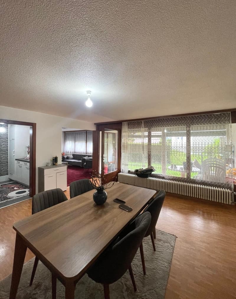 wooden dining table with 4 chairs, floor lamp, plant, cell phone, rug, windows, radiator, cabinet, kitchen