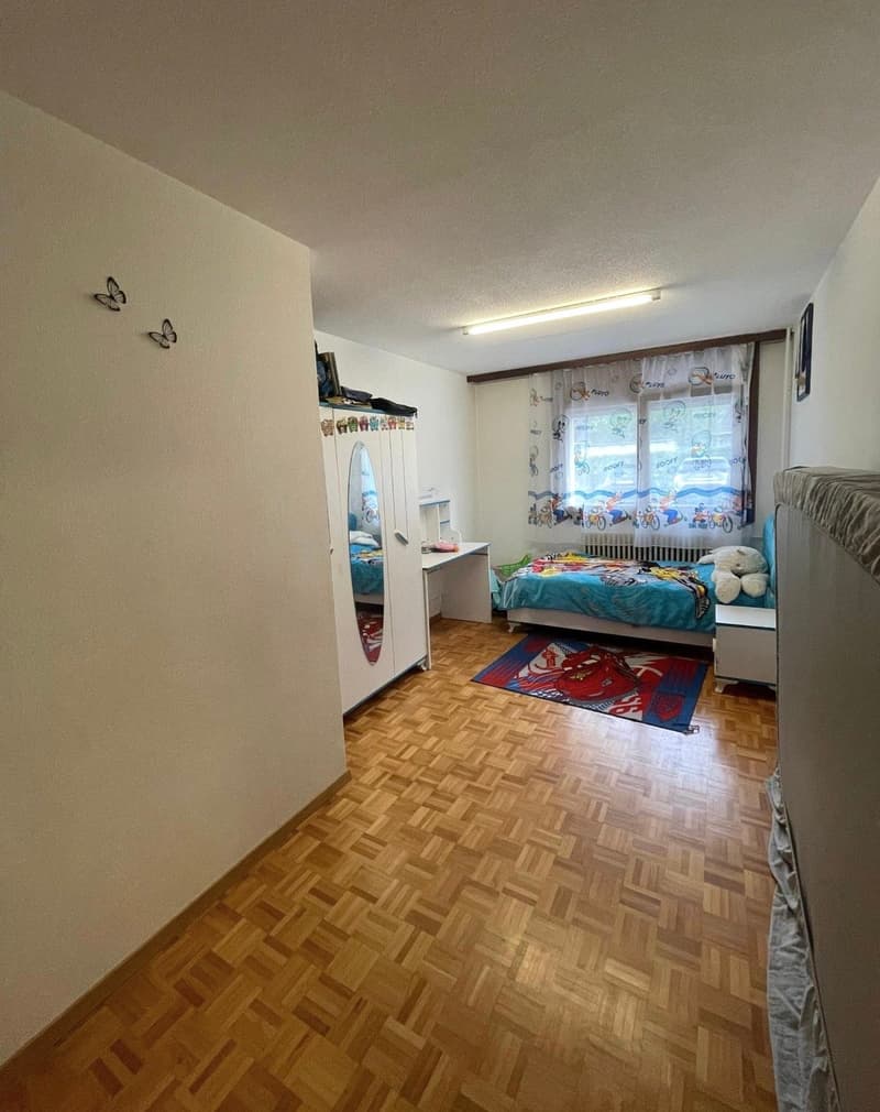 Children's bedroom with bed, desk, wardrobe, carpet, radiator, window with curtains, mirror