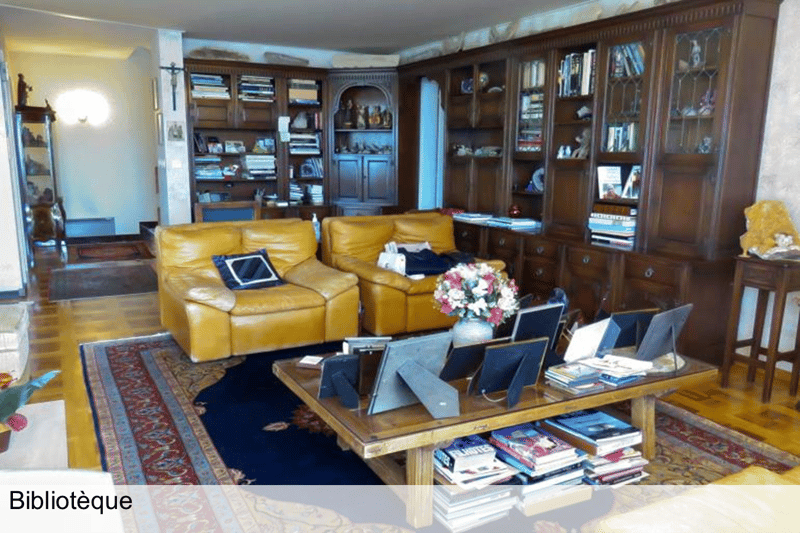 2 yellow sofas, desk with books, large bookshelves, floor lamps, wooden floor