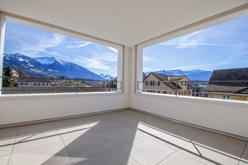 empty room with large windows and balcony, tiled floor, mountain view