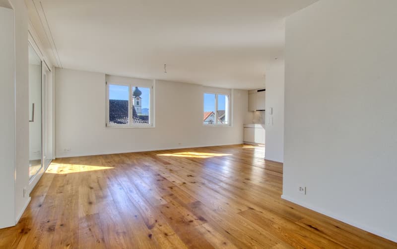 empty room with wooden floor, windows, and a sliding door leading to a balcony