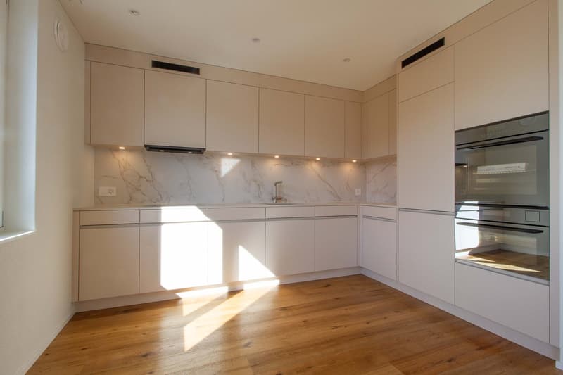 white wooden floor, marble countertops, white cabinets, stainless steel sink and faucet, built-in oven and dishwasher
