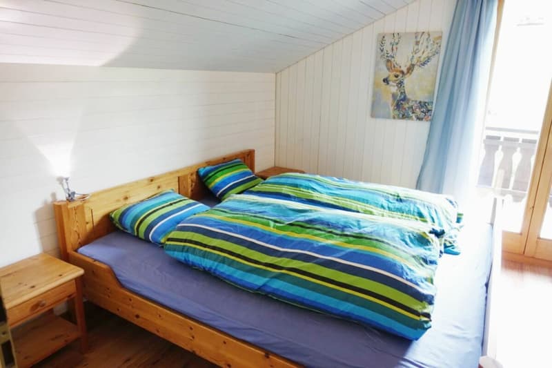 Das Doppelschlafzimmer mit Zugang zum Balkon und Blick auf den Piz Mundaun, Hitzegga sowie die fantastische Bergwelt.