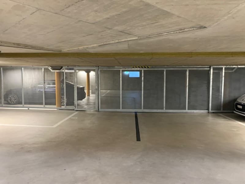 underground parking lot with sliding doors, concrete floor, two cars parked