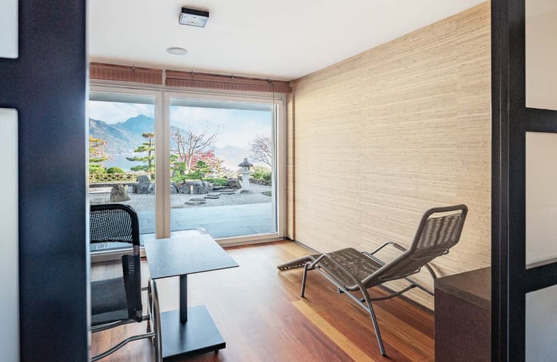 wooden floor, sliding glass door, outdoor garden view, lounge chair, small table, lamps