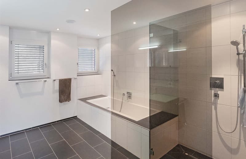 modern white tiled bathroom, bathtub, separate shower, glass walls, towels, and shower head