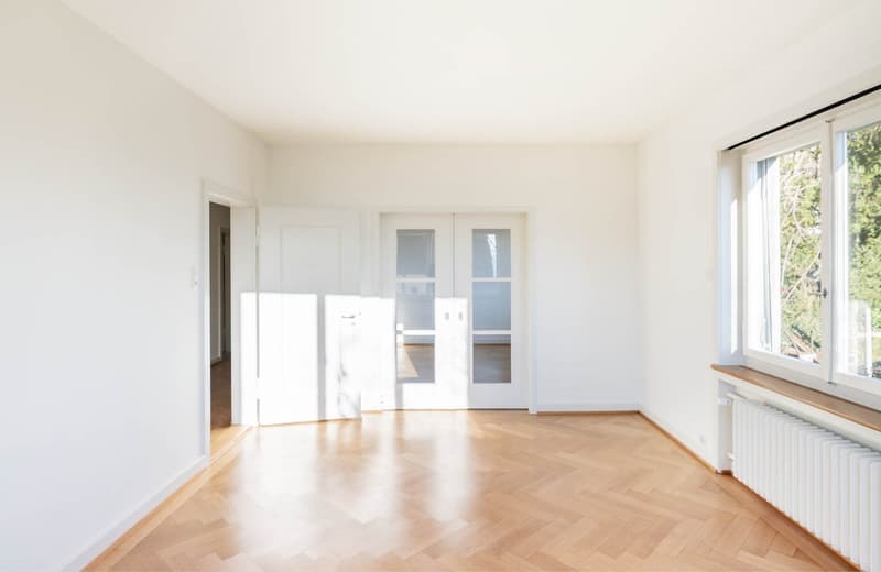 empty room, wooden floor, white walls, 2 doors, windows, radiator