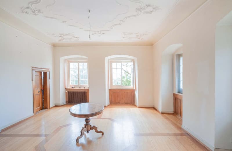 wooden floor, white walls, arched windows, arched window seating, table, wooden doors