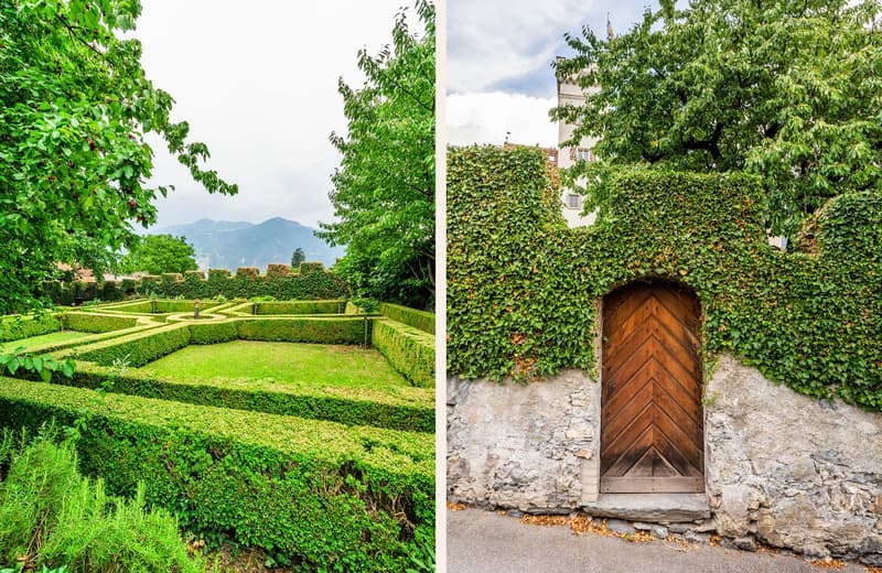 A garden with neatly trimmed hedges, a central fountain, and a view of mountains in the distance. A wooden door covered in ivy is visible on the right side.