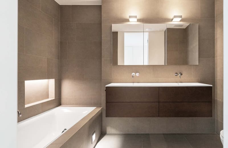 Bathroom with bathtub, double sink, mirror, and tiled walls