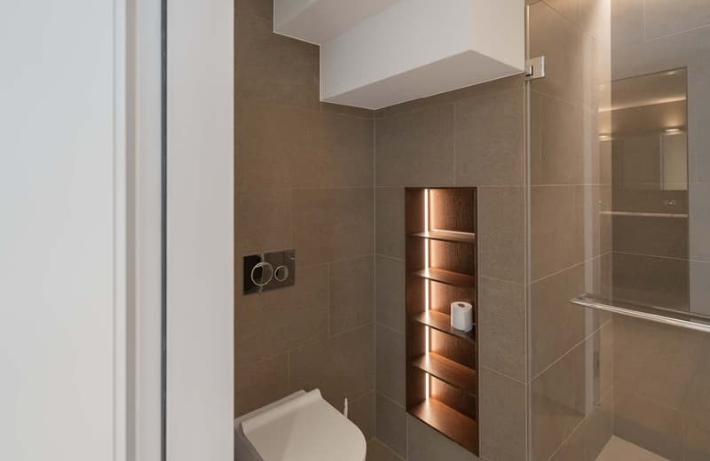 tiled floor, toilet, shower enclosure, recessed shelves, white and brown wooden shelves