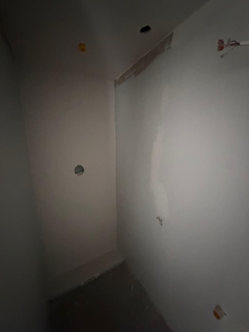 Empty room with white walls, ceiling, and floor. There are holes in the walls and ceiling.