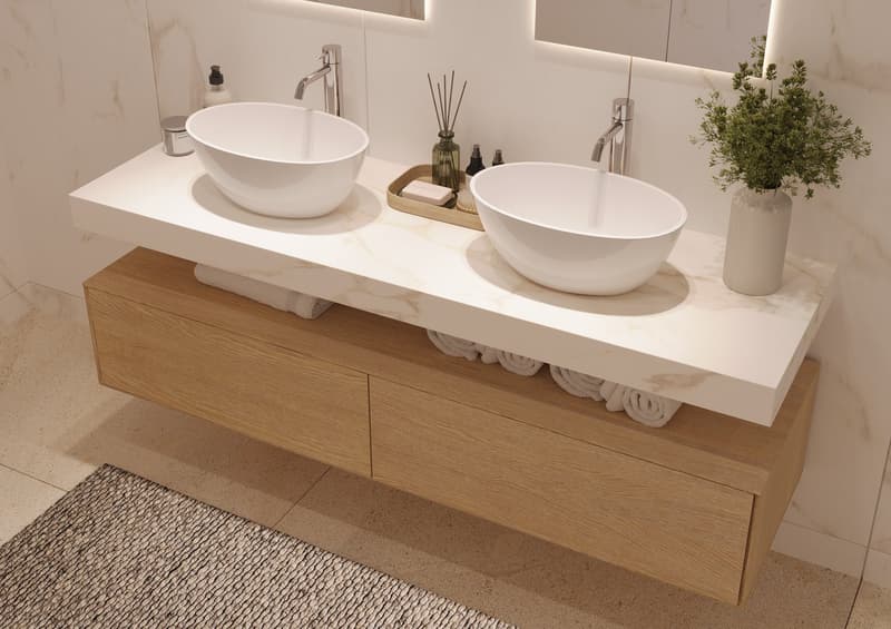 Double sink vanity with two basins, wooden drawers, white marble countertop, two mirrors, wooden tray, soap dispensers, towels, and a plant in a vase.