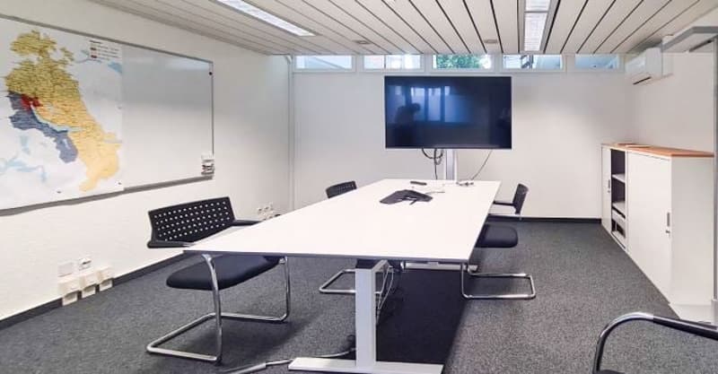 modern office room, white walls, grey carpet, long white table, black chairs, mounted television, whiteboard with map, cabinet in corner