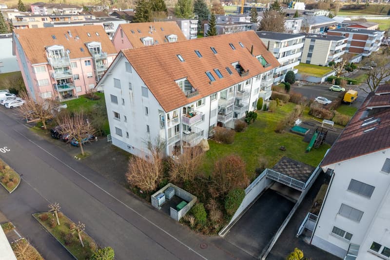 Aerial view of apartment complex with 4 levels, featuring balconies, common garden area, and parking
