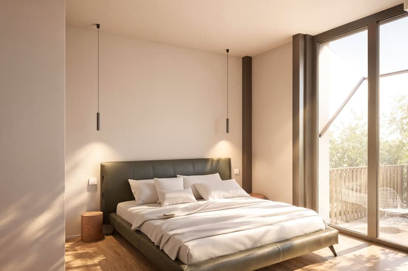 A modern bedroom with a large bed, white linens, a wooden floor, and a balcony with a view of trees.